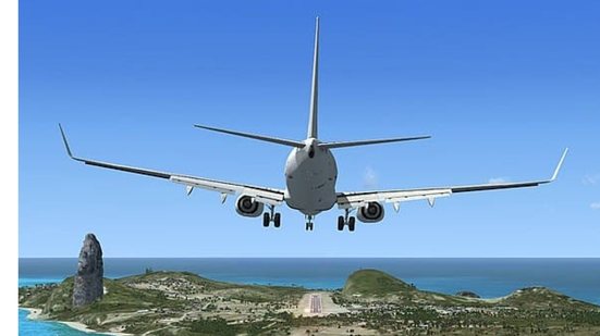 Foto de um avião decolando, é possível ver o céu, o mar, e uma parte da vegetação de um local