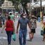 Pessoas andando no meio da rua com sacolas