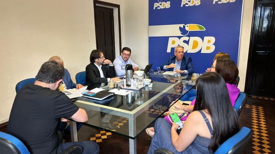 Pessoas sentadas em uma mesa. Estão Álvaro Porto, Diogo Moraes e Débora Almeida. Ao fundo tucano do PSDB