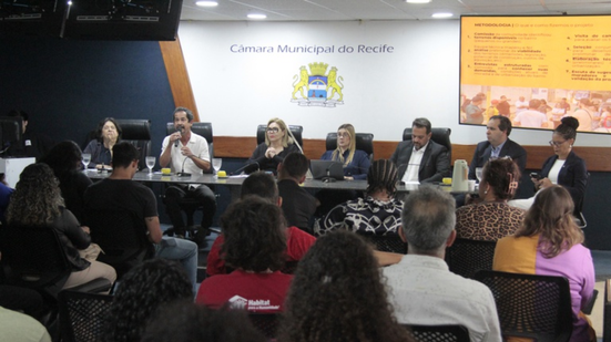Imagem de plateia de costas olhando para mesa com vereadores e representantes da sociedade civil