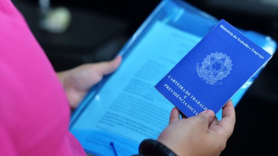 Pessoa com uma pasta e uma carteira de trabalho em mãos