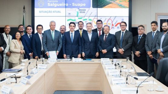 Renan Filho e Silvio Costa Filho ao redor de diversos homens e uma mulher. Ao fundo apresentação de slide mostra salgueiro-suape transnordestina e a frase "situação atual"