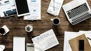 Visão de cima de mesa com vários computadores, agendas, cafés, calculadoras