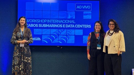 A diretora-presidente Ana Luiza Ferreira em Brasília, acompanhada pela equipe da Adepe, ao fundo, telão com tema do encontro:Workshop Internacional de Cabos Submarinos e Data Centers, evento do Ministério das Comunicações que trata da infraestrutura digita