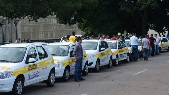 Fila com vários carros escrito autoescola na lateral