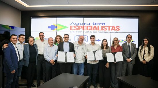 Lado a Lado João Campos, Mozart Sales, Victor Marques estão ao lado de diversos homens e mulheres. Eles seguram 3 pastas de documentos, ao fundo telão tem escrito "Agora tem especialistas"