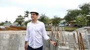 João Campos com capacete de construção coloca a mão em lateral de concreto com algumas estacas