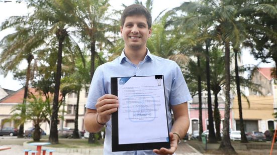 João Campos segurando documento e sorrindo para a câmera