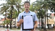 João Campos segurando documento e sorrindo para a câmera