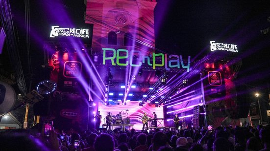 Show com luzes escrito "rec'n'play" diversas pessoas ao redor