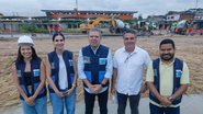 Ricardo Paes Barreto e Túlio Vilaça em frente a uma construção. Duas mulheres e um homem de coletes do governo de Pernambuco sorriem ao lado