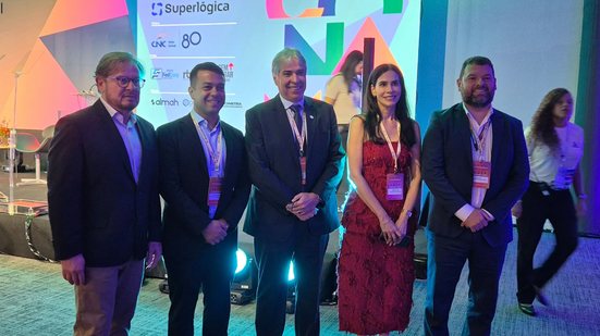 Simone Nunes, Márcio Gomes e outros homens sorriem lado a lado, ao fundo logo do CONAMI