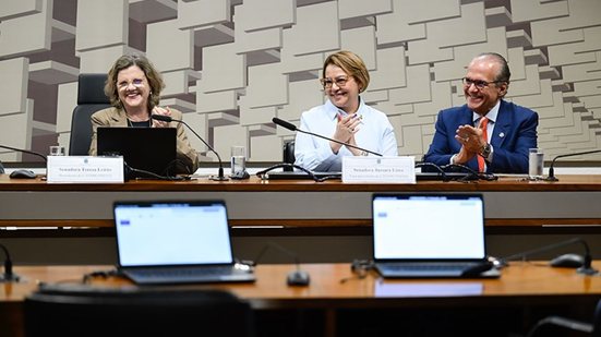 Em bancada do Senado sorriem sentados Teresa Leitão, Jussara e Fernando Dueire