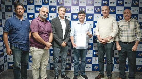 Eduardo da Fonte com documento na mão ao lado de cinco outros homens