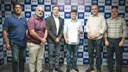 Eduardo da Fonte com documento na mão ao lado de cinco outros homens