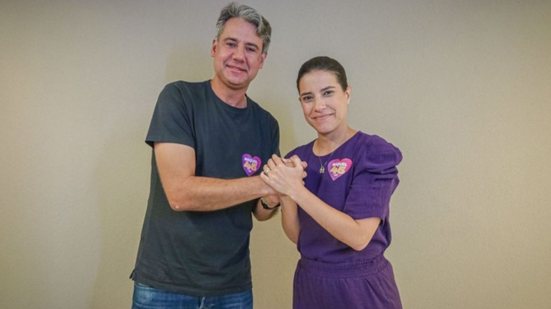 Fernando Monteiro e Raquel Lyra sorriem lado a lado enquanto seguram as mãos uns dos outros