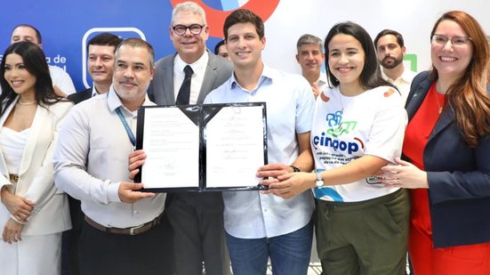 João Campos segura documento ao lado de homens e mulheres, uma delas usa uma camiseta escrito cinpop (centro integrado de atenção à população em situação de rua)
