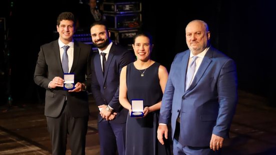 João Campos e Raquel Lyra seguram medalhas entre as mãos, sorriem um homem de barba e o dono do Diário
