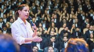 Raquel Lyra fala em pé em microfone, ao fundo diversas pessoas estão sentadas usando preto