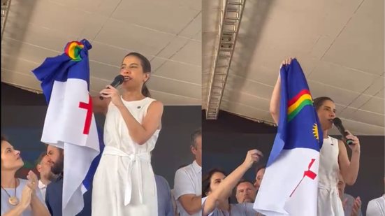 Raquel Lyra segura bandeira de Pernambuco enquanto fala em microfone