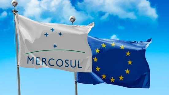 Duas bandeiras. À esquerda, a do Mercosul, à direita, União Europeia. No fundo, o céu.