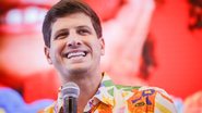 João Campos com camiseta florida sorri enquanto fala em microfone