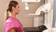 Mulher olha máquina de mamografia