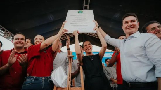 Raquel Lyra e Jader Filho levantando documento.