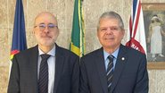 Francisco Bandeira de Mello sorri ao lado de Ricardo Paes Barreto. Ambos são homens brancos mais velhos. Francisco é careca com barba branca e óculos, Ricardo tem cabelo curto grisalho, sem barba e sem óculos