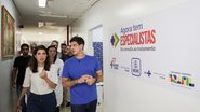 João Campos em corredor ao lado de pessoas. Parede está escrito "Agora tem especialistas"