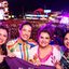 Com roupas carnavalescas, Raquel Lyra, Priscila Krause e duas mulheres sorriem. Ao fundo Palco do Marco Zero com multidão