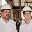 Felipe Cury e João Campos de capacete de construção olham para o lado enquanto conversam
