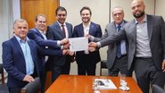Fernando Rodolfo segura papel junto a cinco outros homens que sorriem