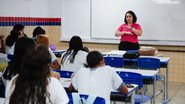 Uma sala de aula de uma escola estadual com uma  professora dando aula