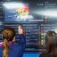 Duas mulheres olham para telão de monitoramento de chuvas da APAC