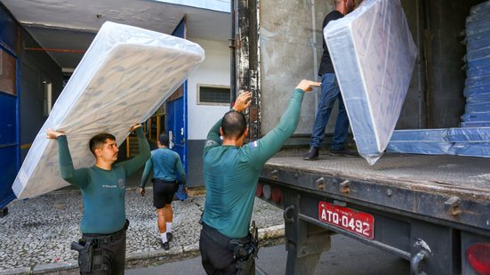 Policiais militares auxiliando na distribuição de colchões à população