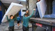 Policiais militares auxiliando na distribuição de colchões à população