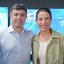 Raquel Lyra abraça Eduardo da Fonte, que sorri. Ele usa um adesivo de campanha de Raquel. Várias pessoas batem palma ao redor