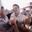 João Campos cumprimenta homem de camisa vermelha enquanto sorri