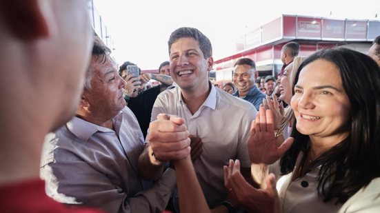 João Campos cumprimenta homem de camisa vermelha enquanto sorri