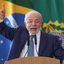 Lula fala ao microfone com dedo apontado para o alto