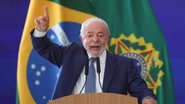 Lula fala ao microfone com dedo apontado para o alto