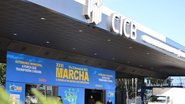 Fachada do Centro Internacional de Convenções do Brasil (CICB) em Brasília, decorada com um grande painel azul da XXVI Marcha a Brasília em Defesa dos Municípios. O painel traz letras amarelas e brancas com o slogan "Autonomia Municipal: A força que transf