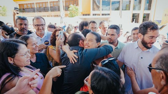 Raquel Lyra, com sorriso, abraça homem em meio à multidão