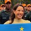 Raquel Lyra segura bandeira de Pernambuco. Ao fundo diversos homens de bonés laranjas com farda da PM