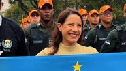 Raquel Lyra segura bandeira de Pernambuco. Ao fundo diversos homens de bonés laranjas com farda da PM