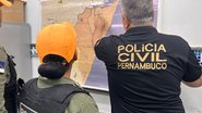 Policial Civil de Pernambuco aponta para mapa de Pernambuco enquanto instrui policial militar