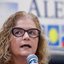 Secretária de Saúde Pernambuco fala ao microfone, na Alepe. Ao fundo, o símbolo da Alepe