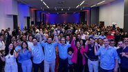 Multidão em auditório levanta as mãos juntos. Na frente estão Felipe Alecrim, Renato Antunes, Romeu Zema, Eduardo Moura e Carlos Sant'anna