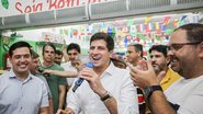 João Campos fala ao microfone ao redor de diversas pessoas